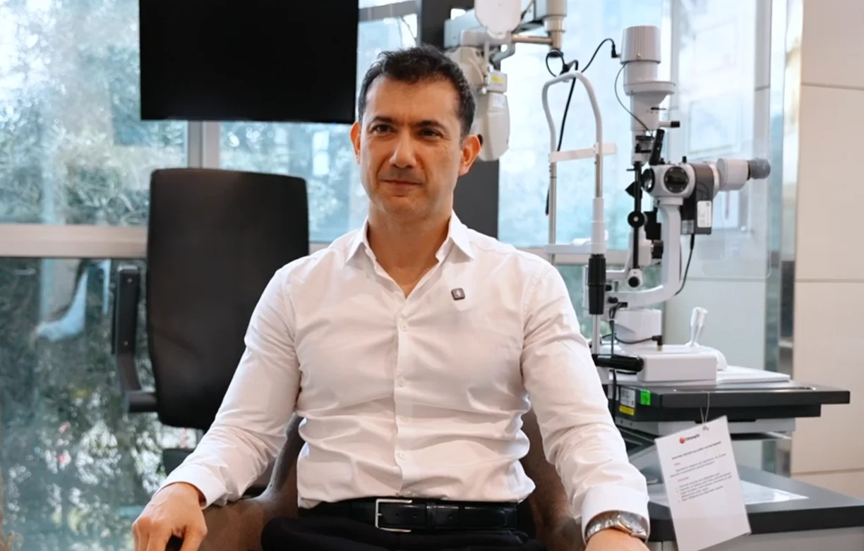 Prof. Dr. Alper Ağca Medicana Ataköy Hastanesi'ndeki muayene odasında, sağında biyomikroskop duruyor